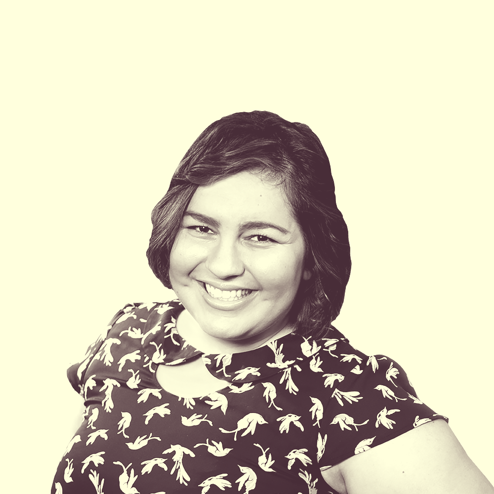 A young Latina with dark brown wavy hair wearing a black patterned dress.