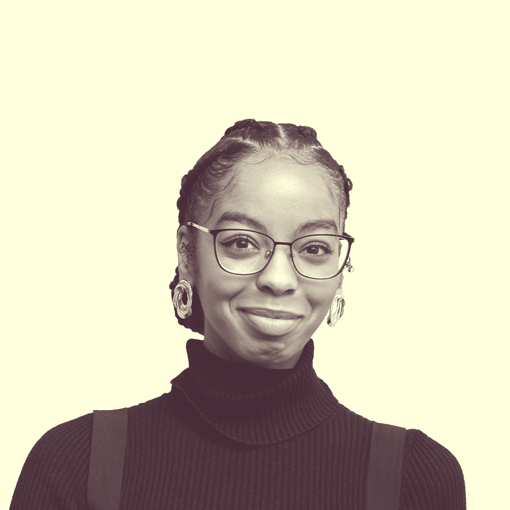 A young Black woman who is smiling in suspenders.