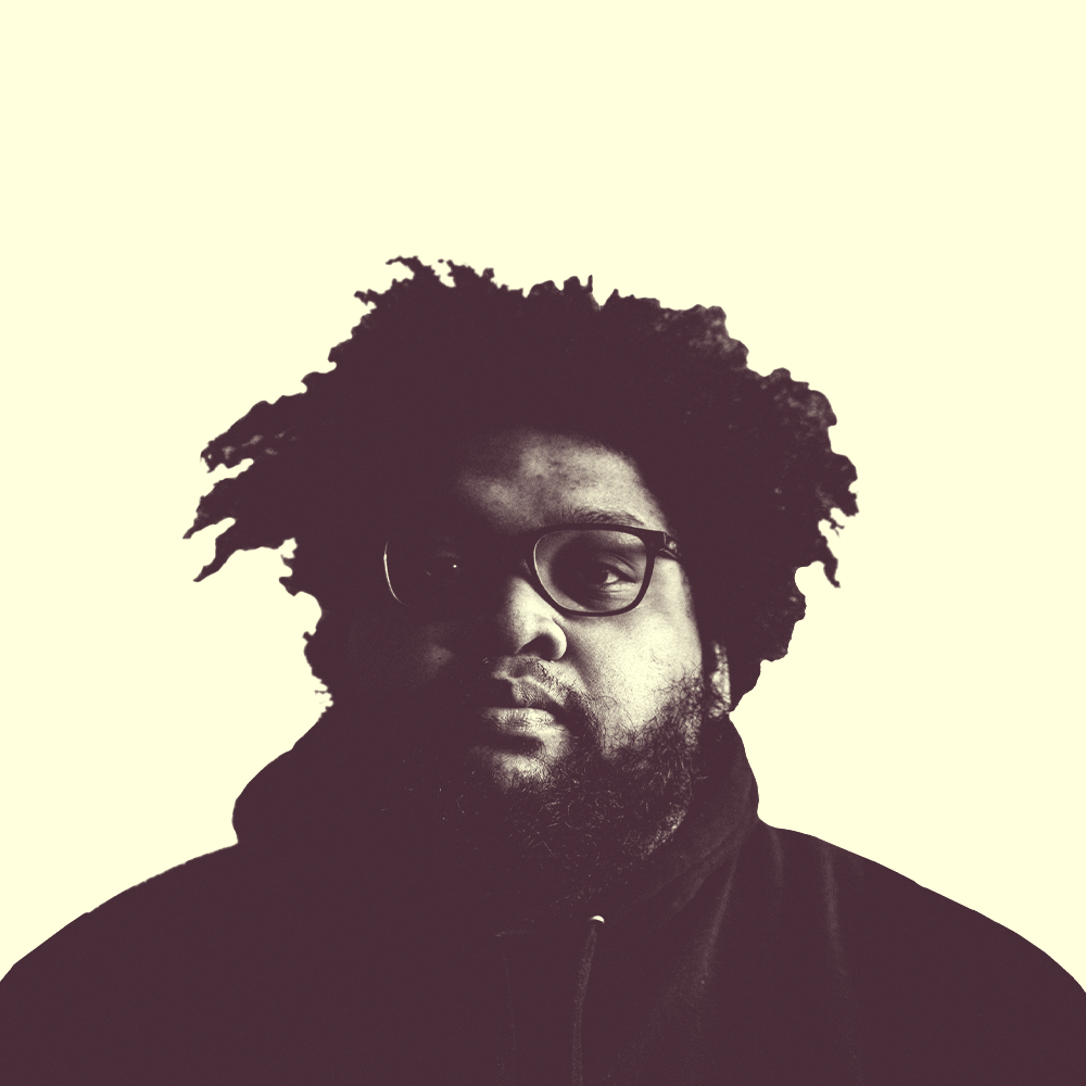 A young African American man with an afro and wearing glasses