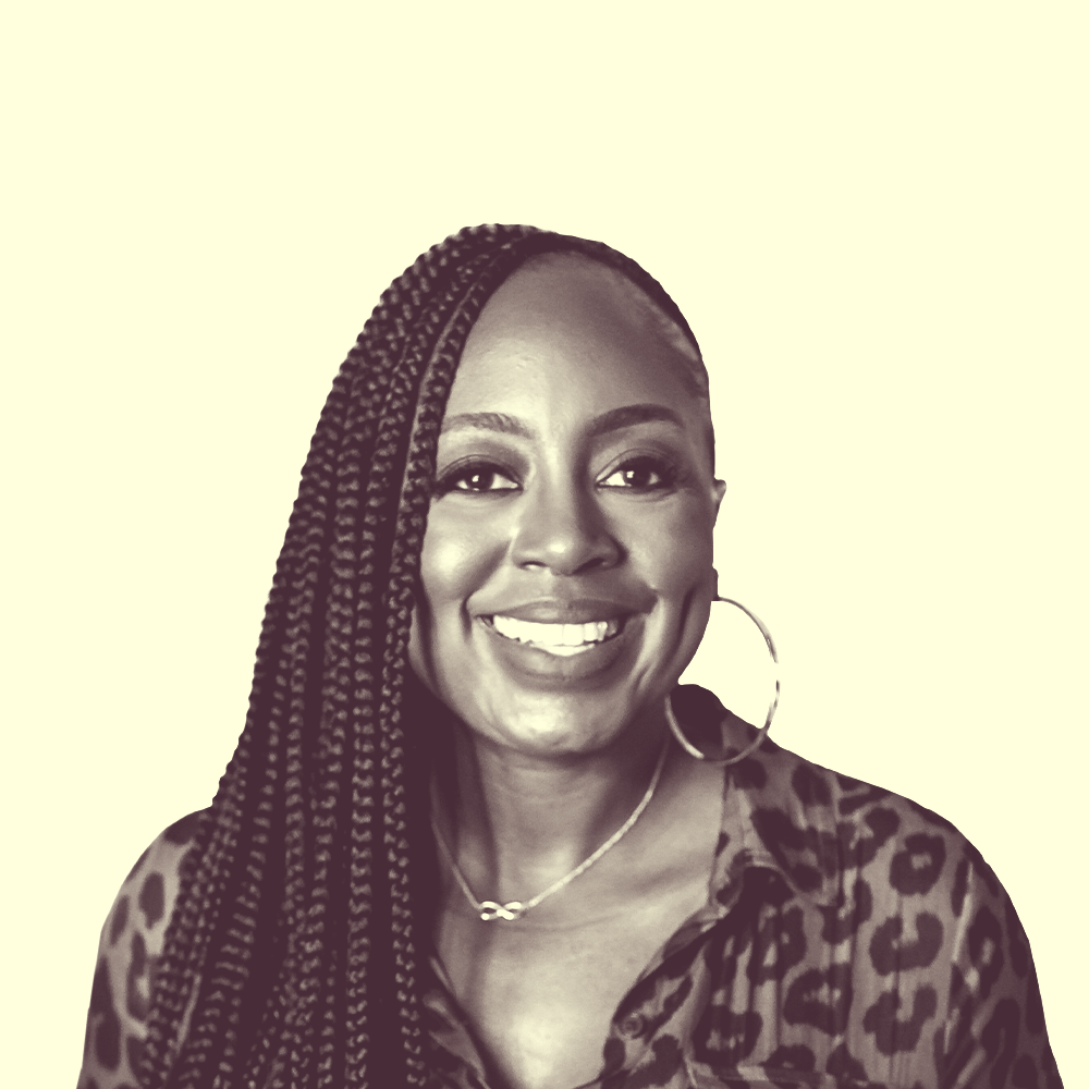 An African-American woman wearing a leopard top, long braids, red lipstick and smiling.