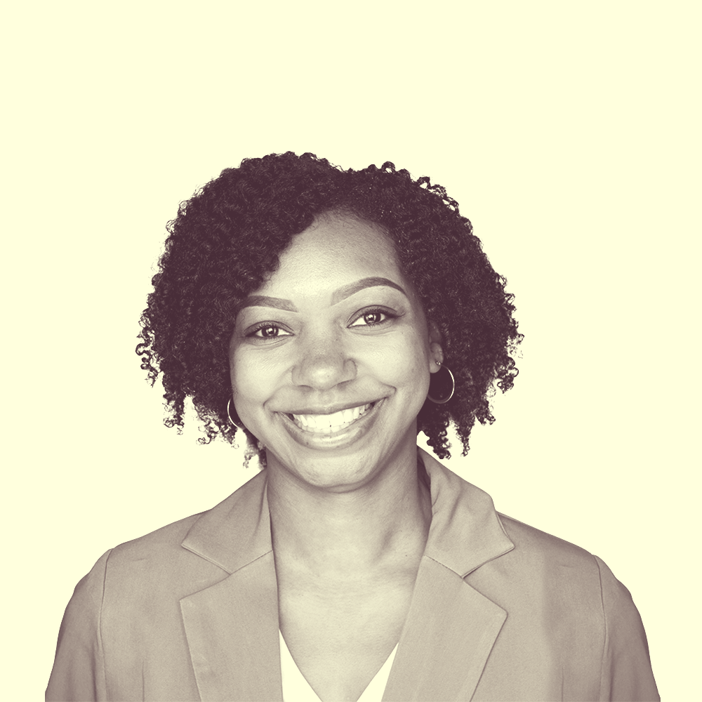 A young, smiling African American woman wearing a cute pink blazer